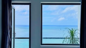 Una habitación con dos ventanas amplias que dan al mar y un pequeño bote.
