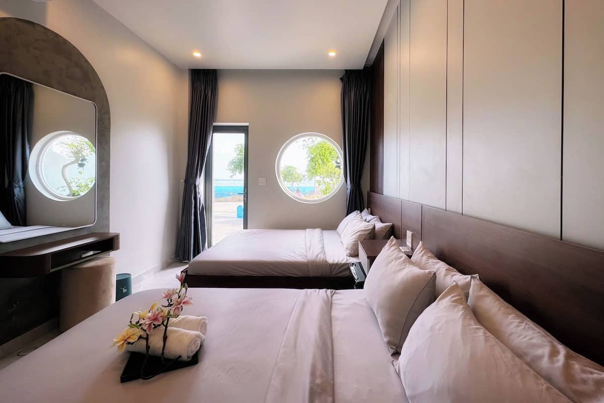 Habitación de hotel con dos camas, un espejo grande y vista al exterior.