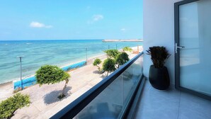 Un balcón con vista al mar, a una playa y un cielo despejado.