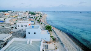 Un pueblo costero con edificios a lo largo de la playa, vistas claras del mar y un muelle con barcos.