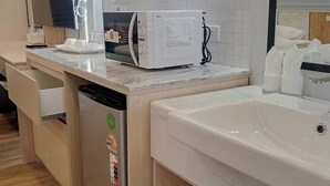 A modern kitchen with a built-in microwave, a dishwasher, and a large sink. - Wellness World Chiva 89 (Bangkok)