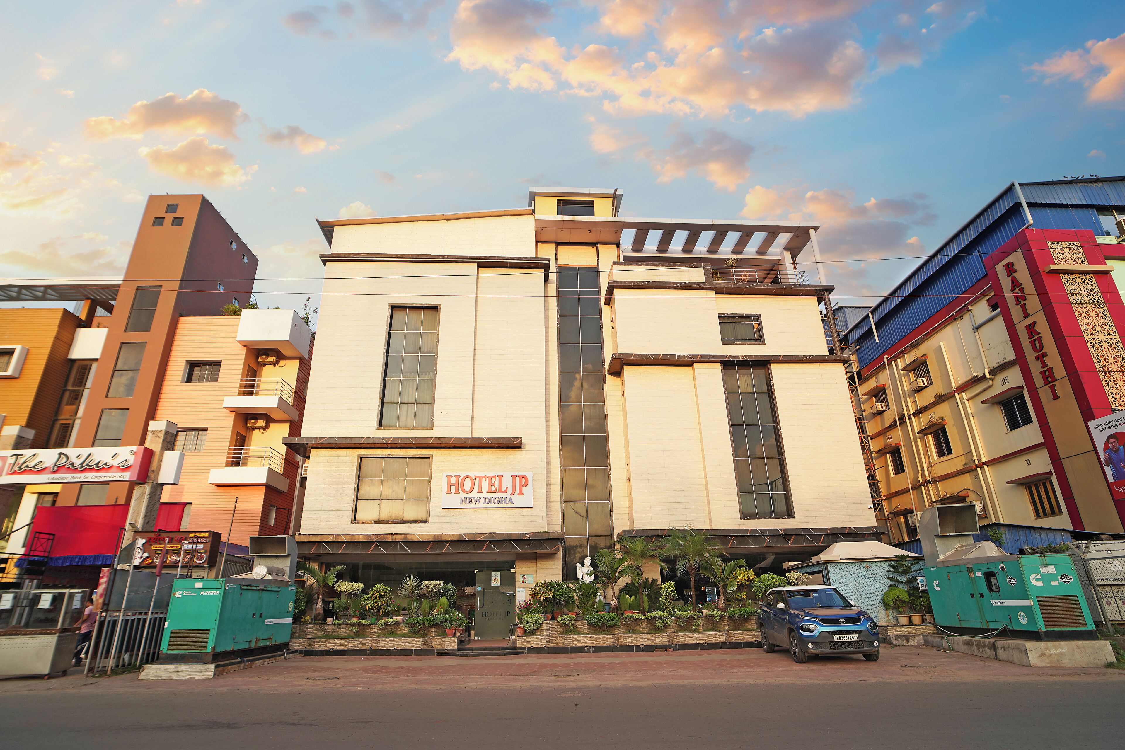 A hotel with a modern facade, a signboard, and a parking area.