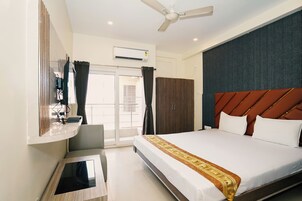 Una habitación de hotel con cama, escritorio, espejo, aire acondicionado y armario.