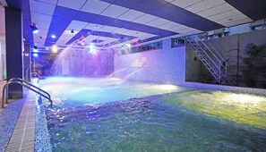 An indoor swimming pool with a water feature, a sign indicating 'HOTEL JP', and a staircase leading to an upper level. - HOTEL JP (Kanthi)