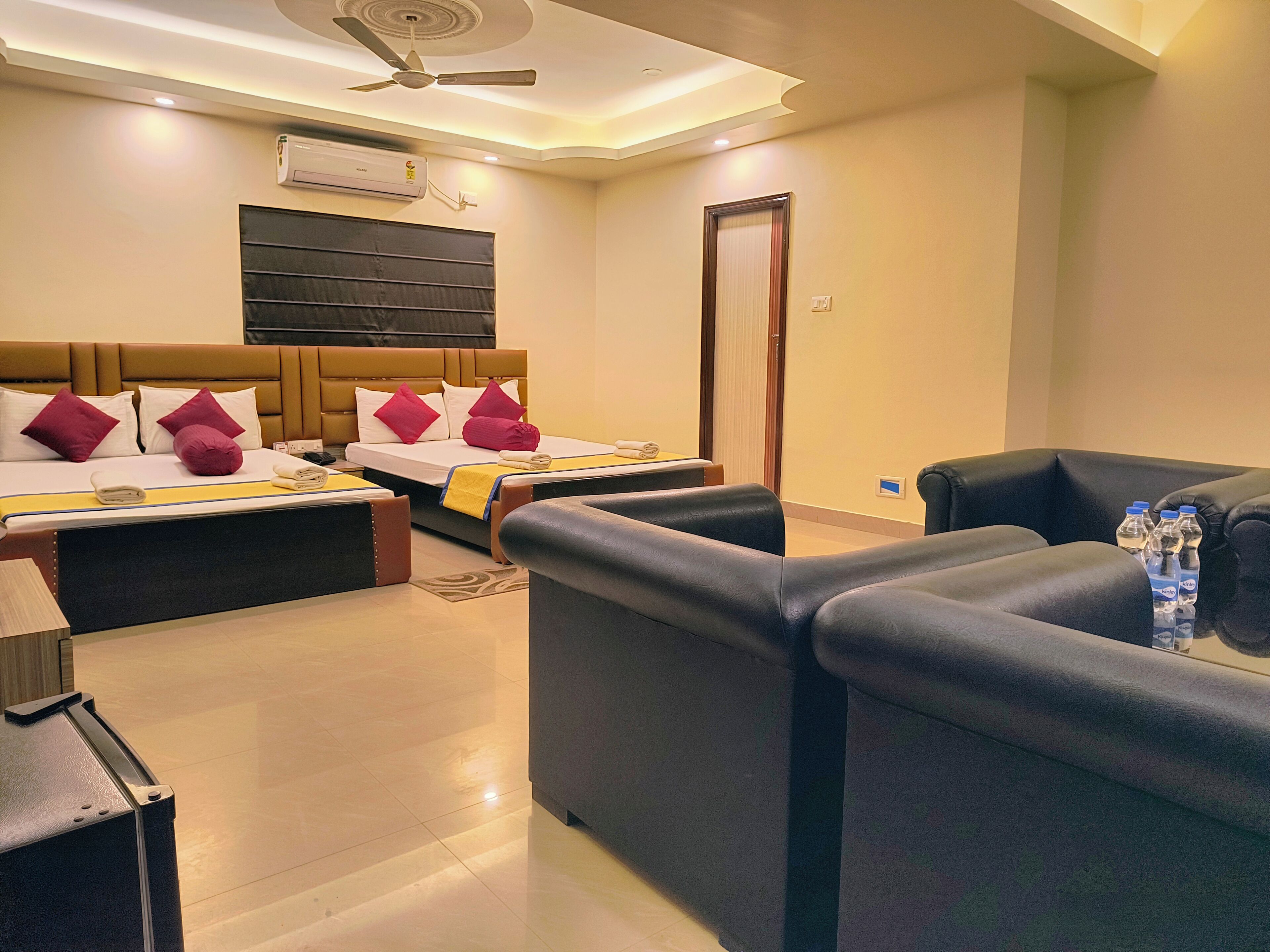 A hotel room with a bed, a sofa, a desk, and a ceiling fan.