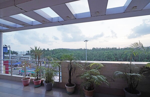 A balcony with potted plants, a view of a cityscape, and a cloudy sky. - HOTEL JP (Kanthi)