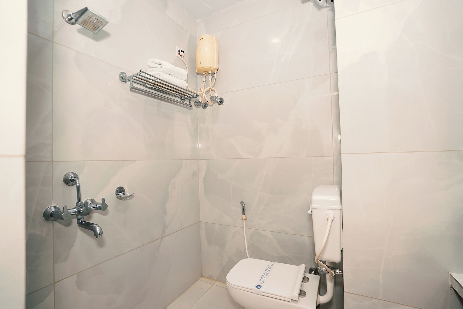 A bathroom with a toilet, a shower, and a towel rack.