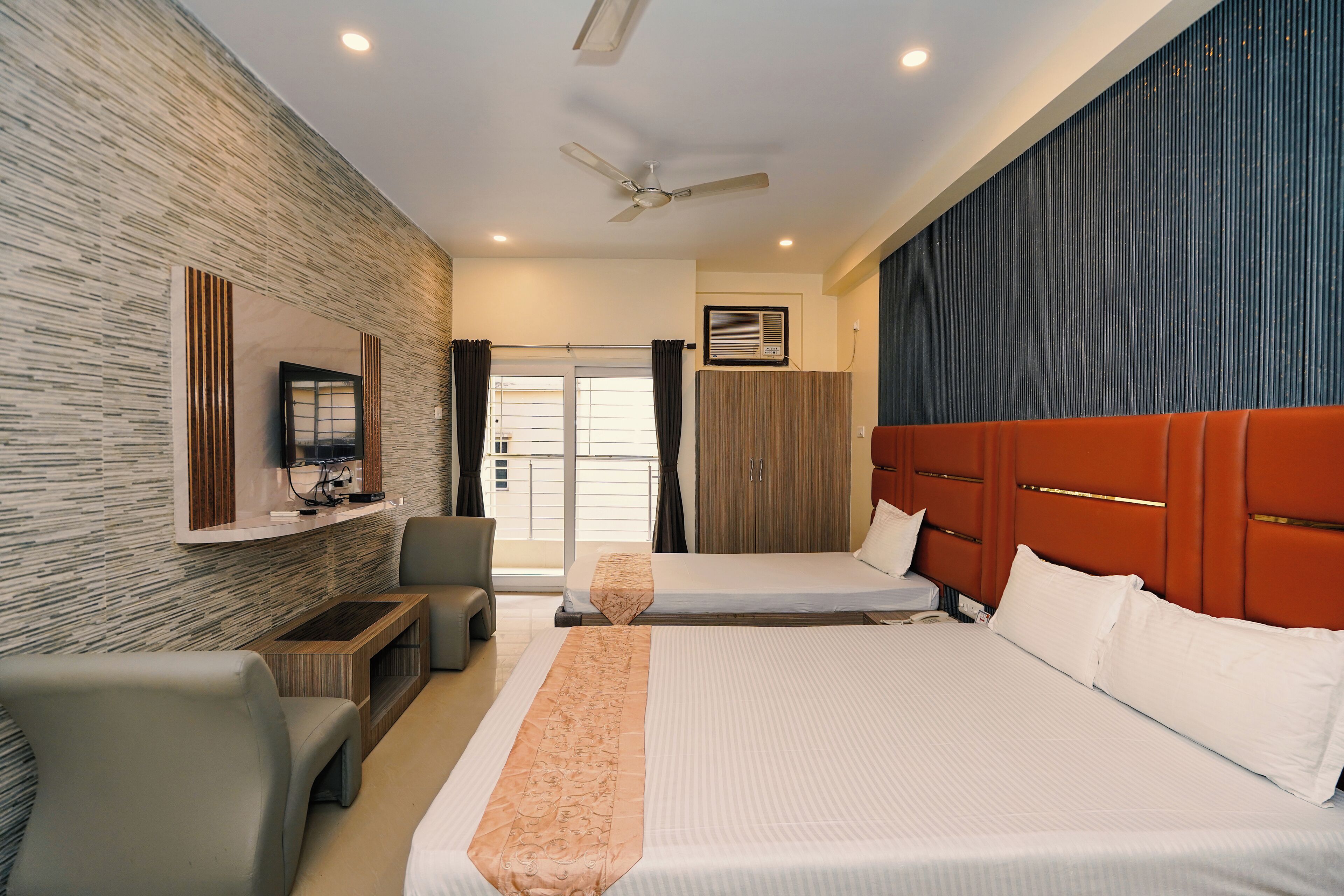 A hotel room with two beds, a TV, a desk, and a wardrobe.
