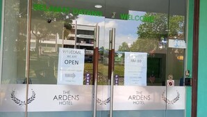 En hotellentrén med glasdörrar, en välkomstskylt och en prisskylt som visar priset 80 ringgit.