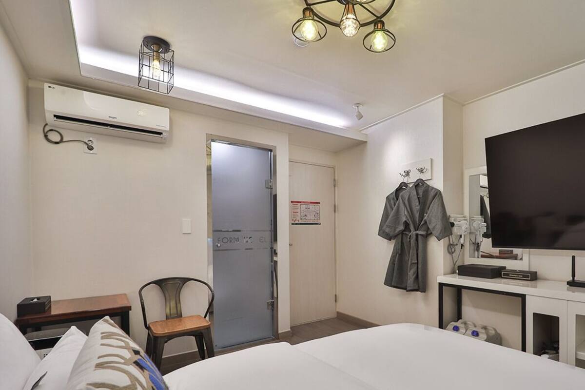Une chambre d’hôtel équipée d’un lit, d’un bureau, d’une chaise, d’une télévision et d’un appareil de climatisation.