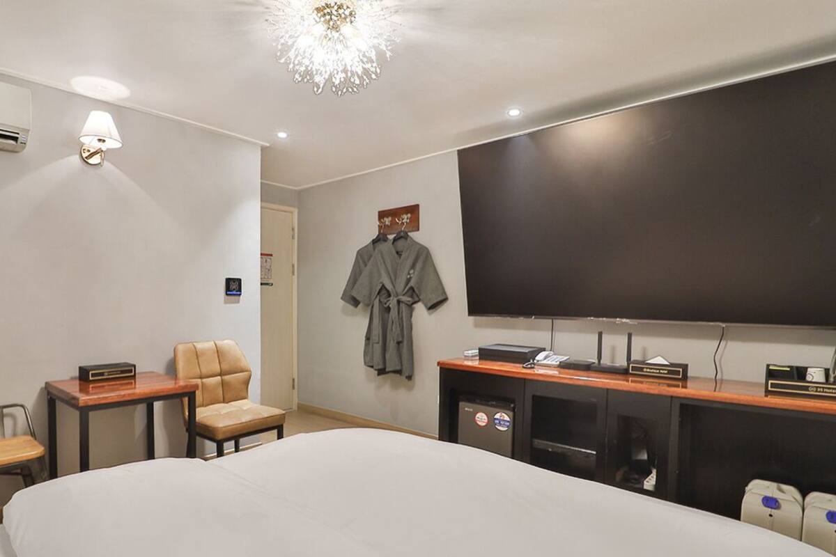 Une chambre d’hôtel avec un grand lit, un bureau avec un ordinateur, une chaise, une télévision et un appareil de climatisation.