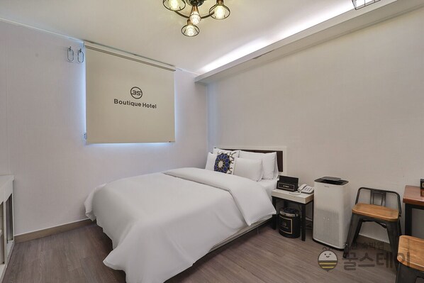 Una habitación de hotel con cama, mesita de noche, silla y un cartel en la pared que dice 'Boutique Hotel'.