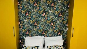 A bed with white linens, two pillows with geometric patterns, and a headboard with a floral design. - Apartment Paris 11 - 2 bedrooms - 2 shower rooms - 2 toilets (Paris)