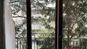 A view through a window with a metal balcony railing, trees, and a building in the background. - Apartment Paris 11 - 2 bedrooms - 2 shower rooms - 2 toilets (Paris)