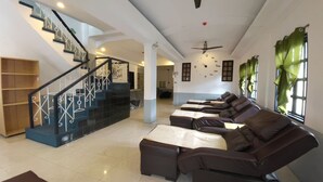Un vestíbulo de hotel con una escalera, una zona de estar con sofás y una recepción.