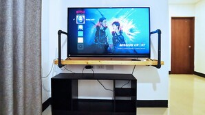 Un televisor sobre un atril de madera en una habitación con una puerta al fondo.