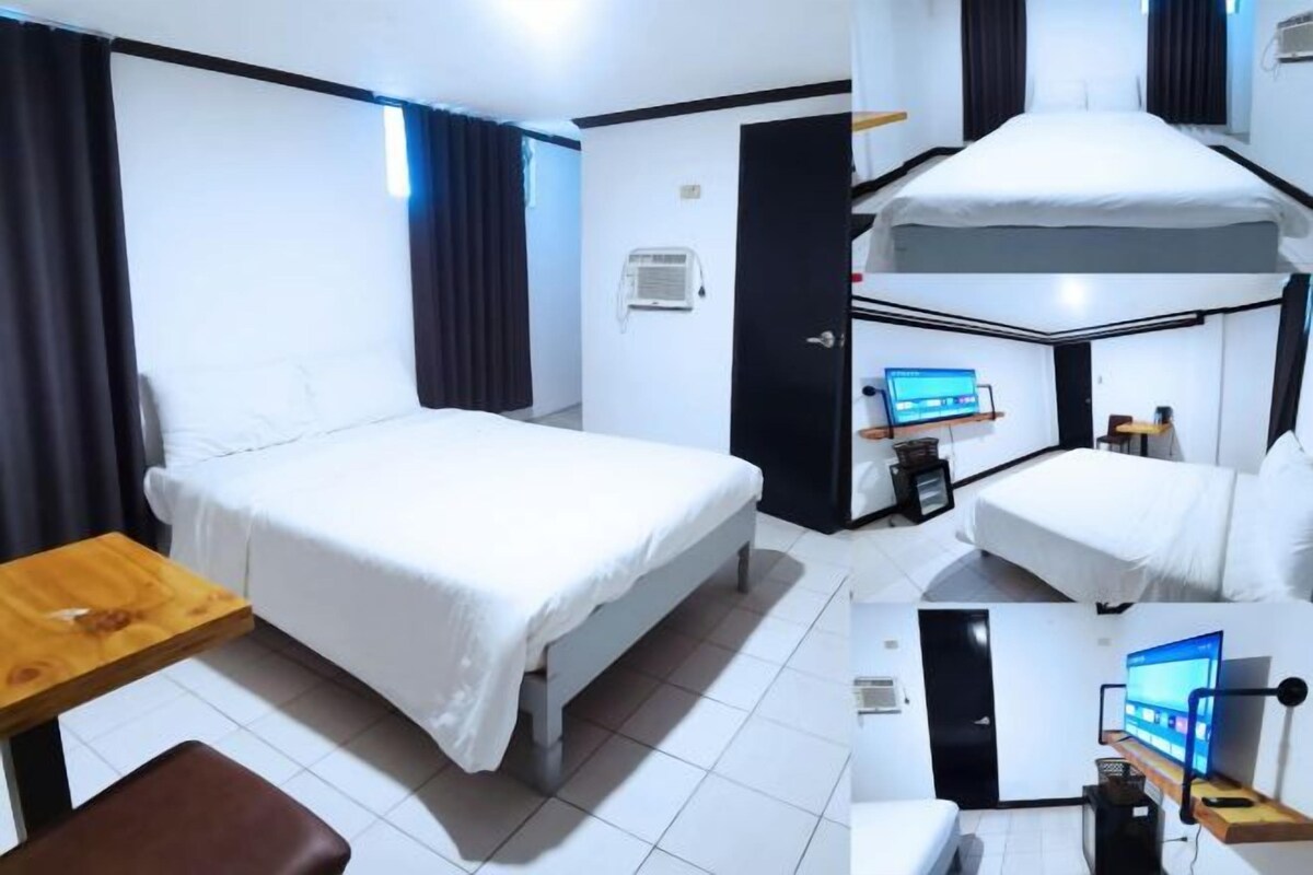 A hotel room with a bunk bed, a single bed, a desk with a chair, and a television.