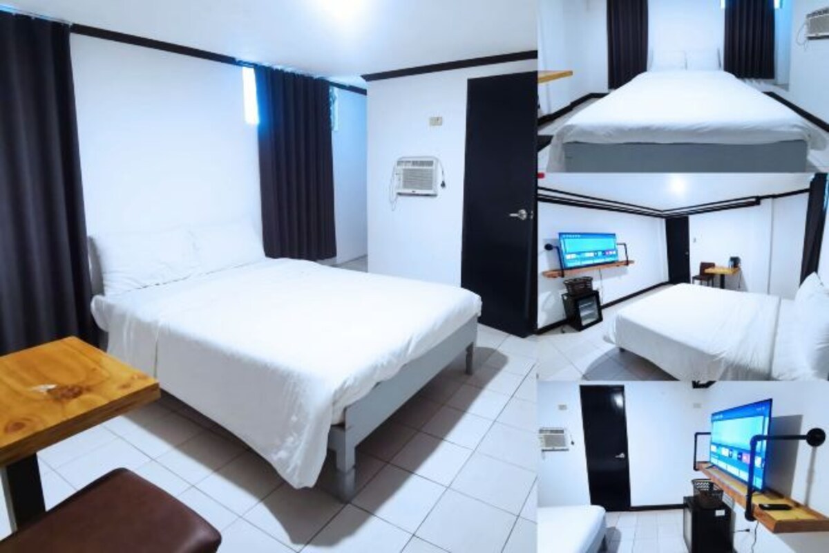 A hotel room with a single bed, a desk, a chair, a TV, and a small table.