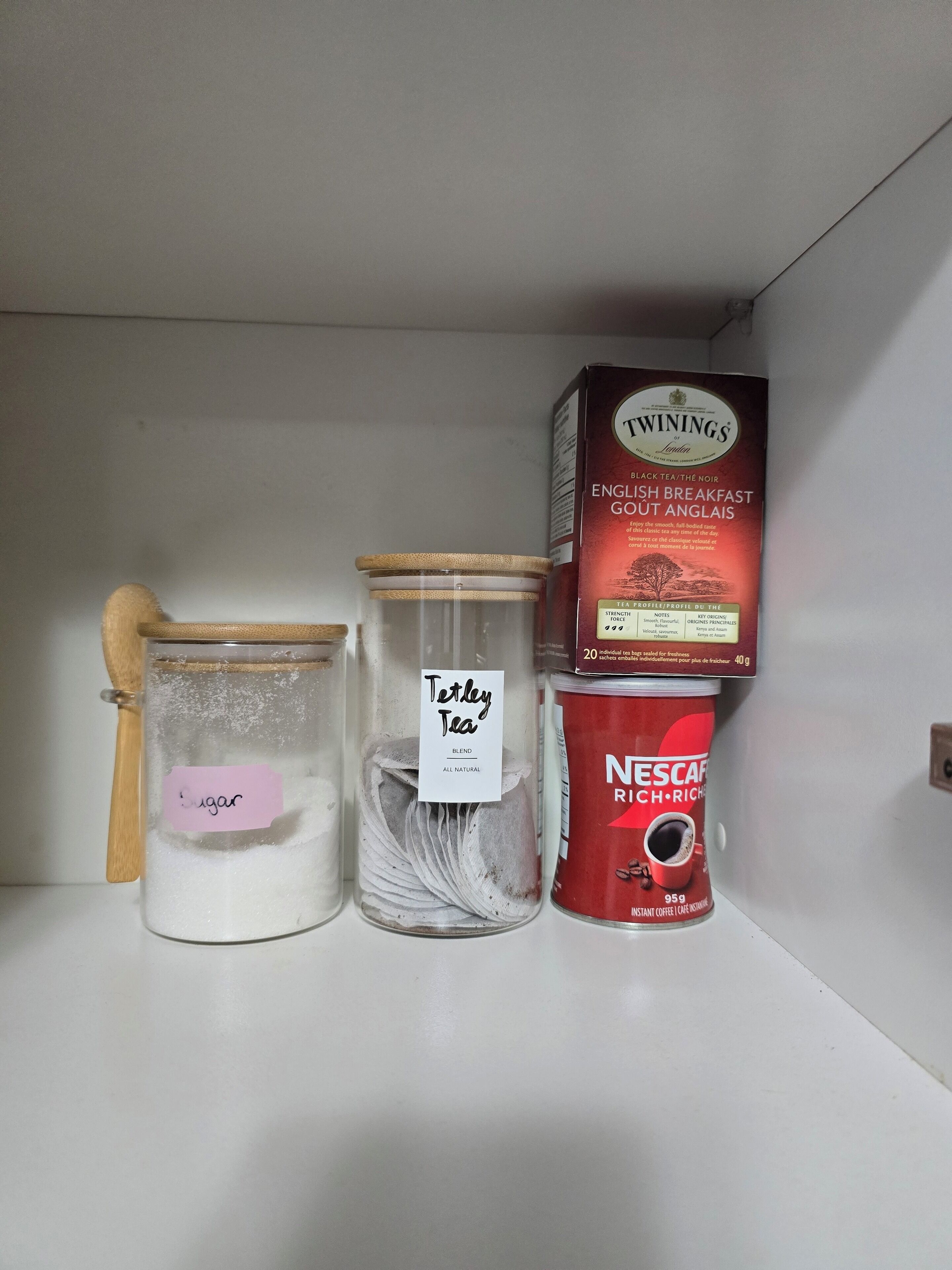 Ein Regal mit Zuckerbehälter, Teedose und einer Packung Instantkaffee.
