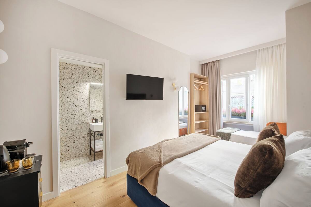A hotel room with a bed, a TV, a wardrobe, and a bathroom.