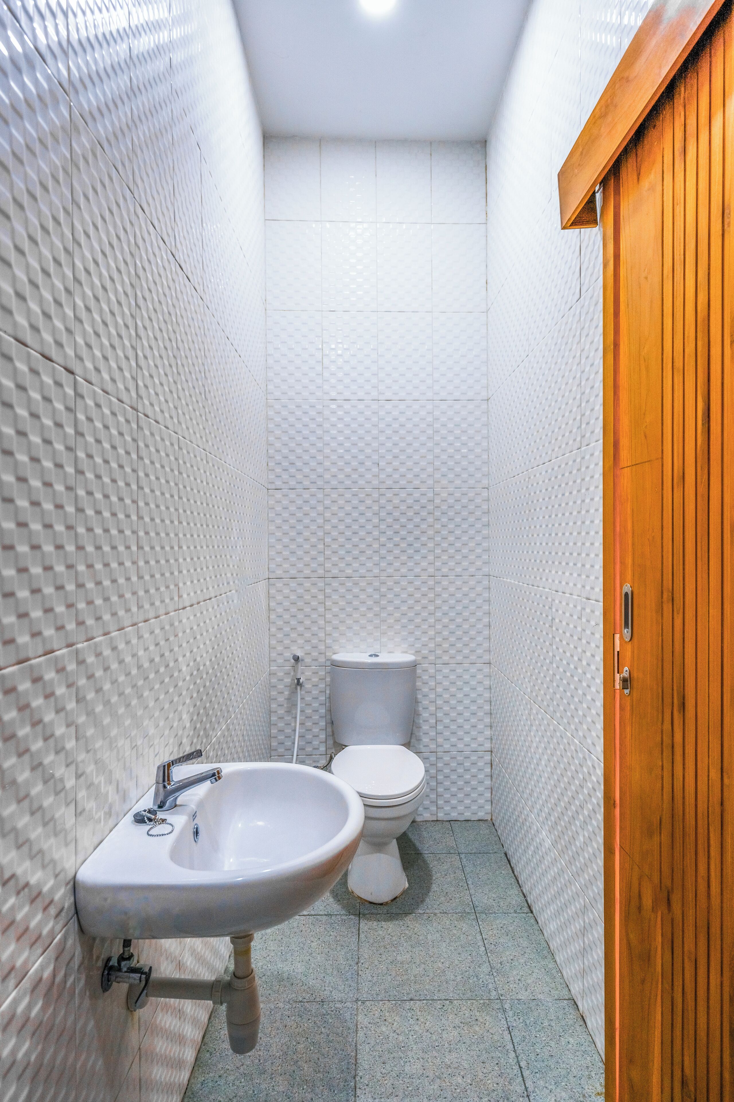 Une salle de bain avec un lavabo blanc, des toilettes et une porte en bois.