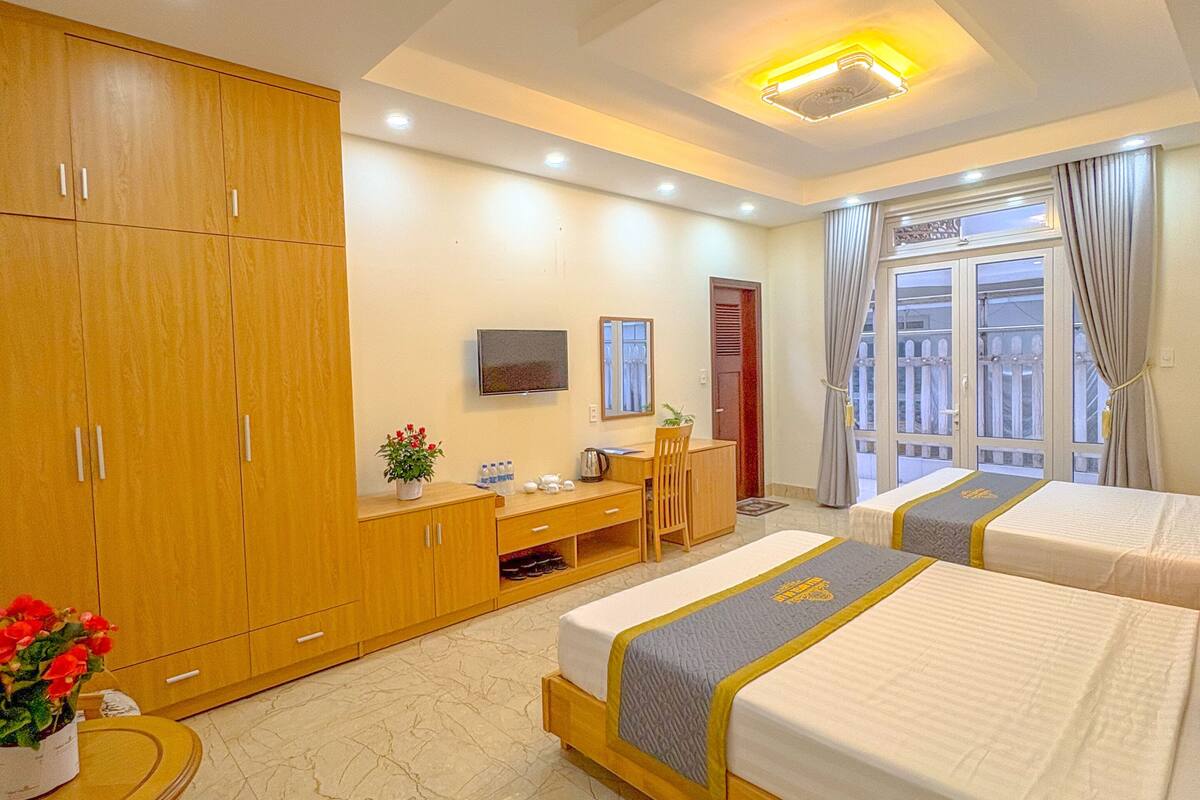 A hotel room with two beds, a desk, a TV, and a wardrobe.