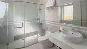 Ein modernes Badezimmer mit einer gläsernen Duschkabine, einer Toilette und einem Waschbecken mit Spiegel darüber.
