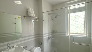 Ein modernes Badezimmer mit Duschkabine aus Glas, einem großen Spiegel und einem weißen Waschbecken.