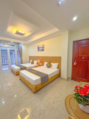 A hotel room with two beds, a wooden headboard, a large window with curtains, a red door, and a small table with a vase of flowers. - Sam Villa Hotel Dalat (Xuan Huong - Da Lat)