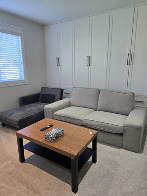 Un salon avec un canapé gris, une table basse en bois et un fauteuil gris.