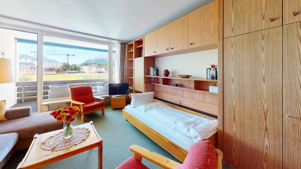 Une chambre d’hôtel moderne équipée d’un lit, d’un canapé, d’une télévision et d’une grande fenêtre donnant sur l’extérieur.