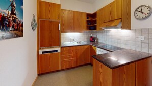 Une cuisine avec des meubles de rangement en bois, un évier et une horloge au mur.