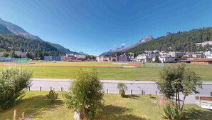 Un terrain de sport doté d’une piste d’athlétisme, entouré de bâtiments et de montagnes.