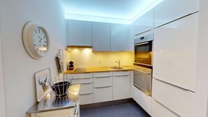 Une cuisine moderne avec des armoires blanches, un four en acier inoxydable et une horloge au mur.
