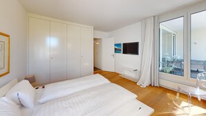 Une chambre moderne avec un grand lit, une armoire, une télévision et un balcon avec vue.