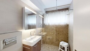 A modern bathroom with a large mirror, a sink, and a shower area. - Well-kept holiday apartament house in a prime location in St. (St. Moritz)