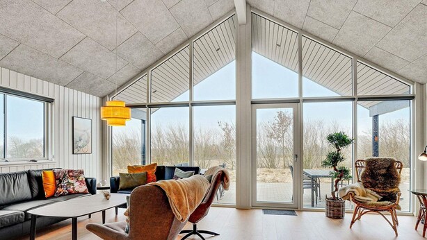 A spacious living room with a large glass door leading to an outdoor area, a sofa, a coffee table, and a chair. - 16 Person Holiday Home in Sydals (Sydals)