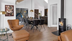 Un salon moderne avec un coin repas, une cheminée et une grande fenêtre.