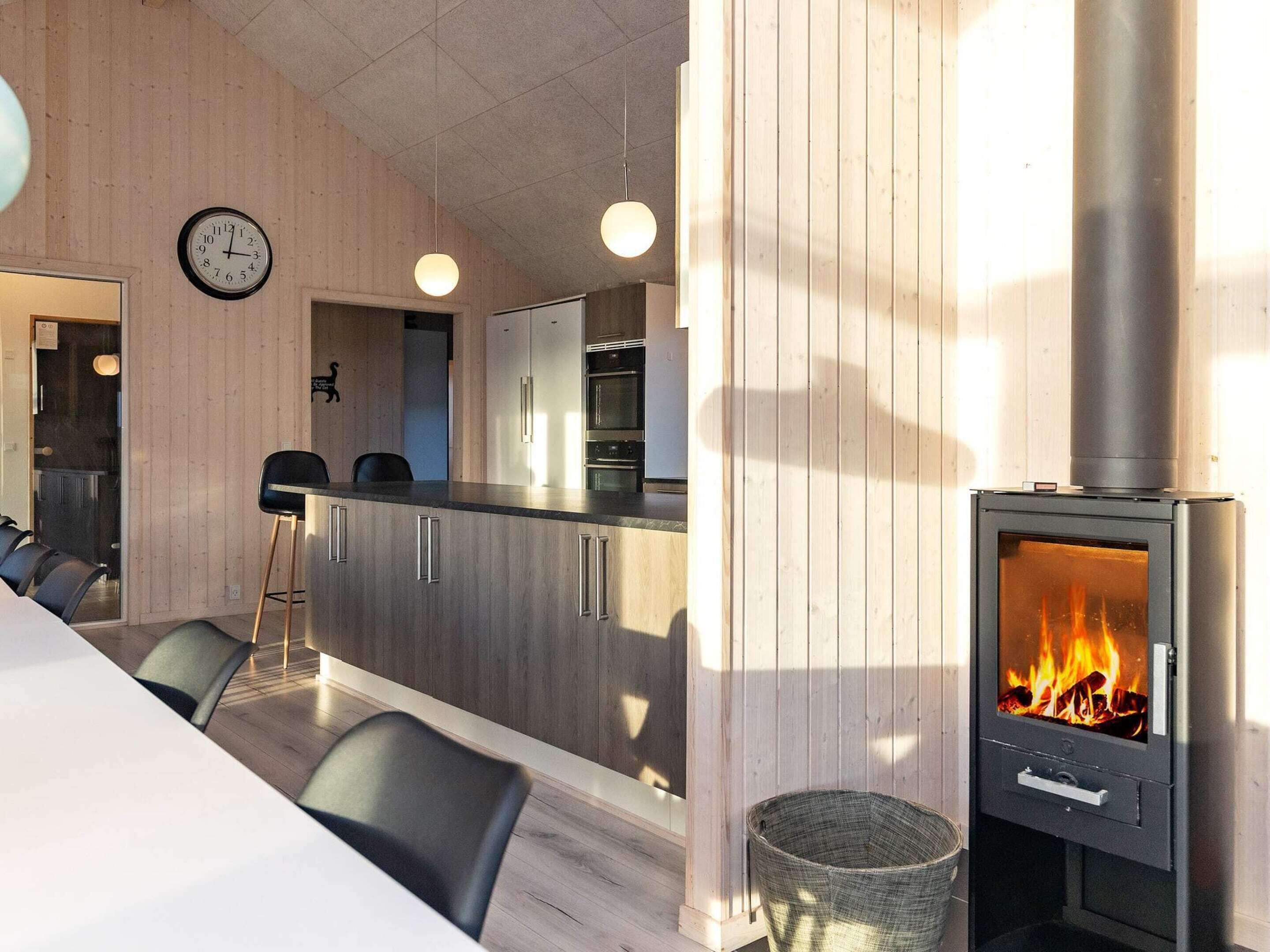 Moderni keittiö, jossa on keskeinen saareke, puuhella ja ruokailutila tuoleineen.