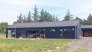 Une maison moderne dotée d’un patio couvert, de grandes fenêtres et d’un garage numéroté 6.