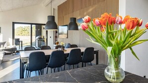 Un espace repas moderne avec une table en marbre, des chaises noires et un vase de tulipes.