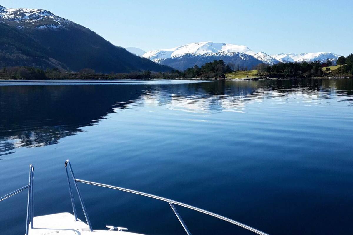A boat on a calm lake with mountains in the background.
