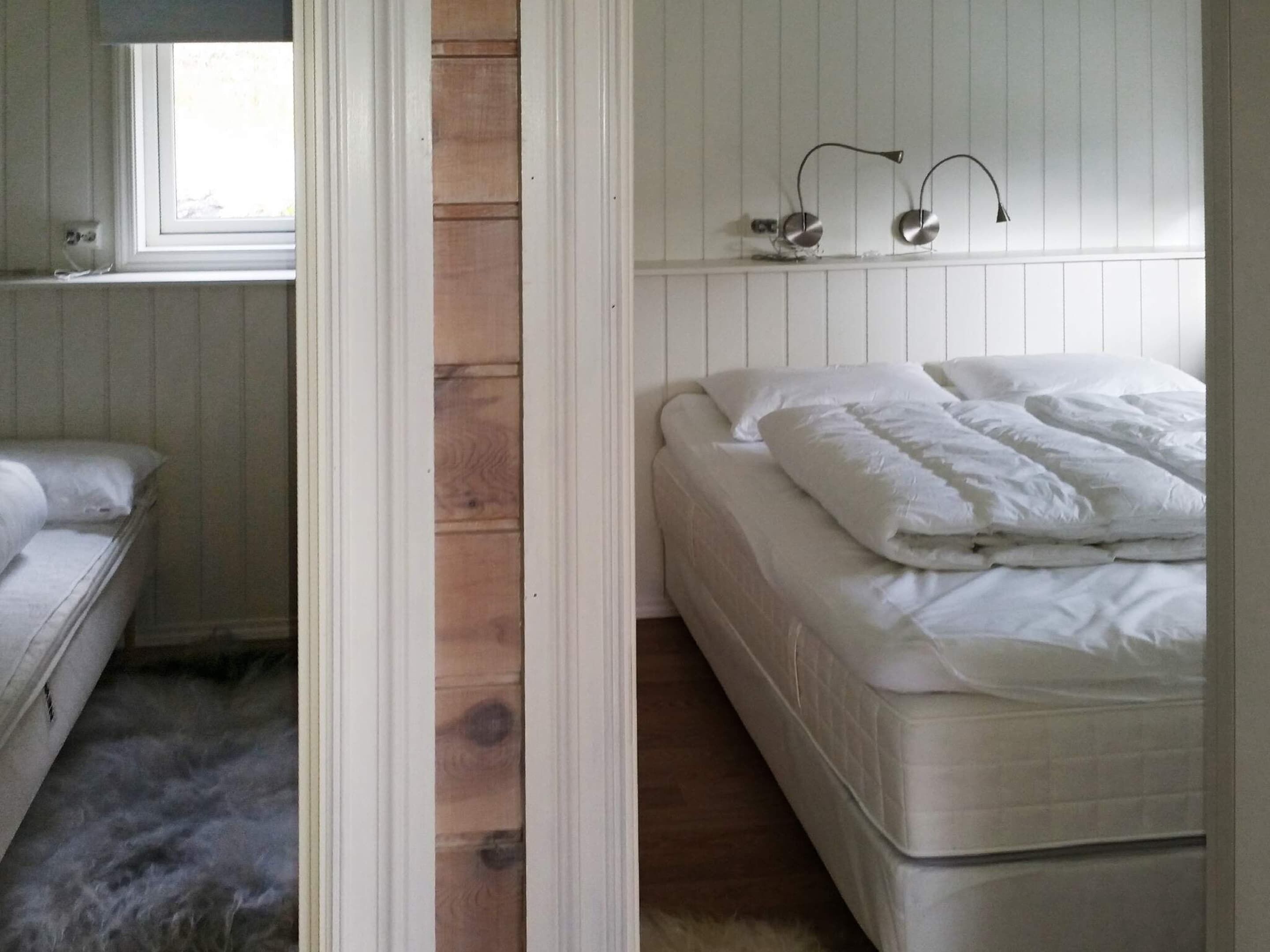 A bedroom with a bed, a window, and a wooden wall.
