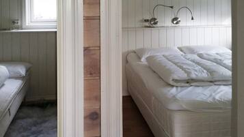 A bedroom with a bed, a window, and a wooden wall.