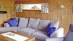 Un salon chaleureux avec un canapé gris, des coussins bleus, une table basse en bois et une lampe.