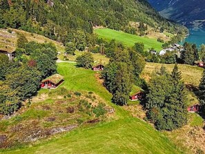 A mountainous landscape with several red-roofed cabins, a winding path, and a lake in the background. - 6 Person Holiday Home in Olden (Stryn)