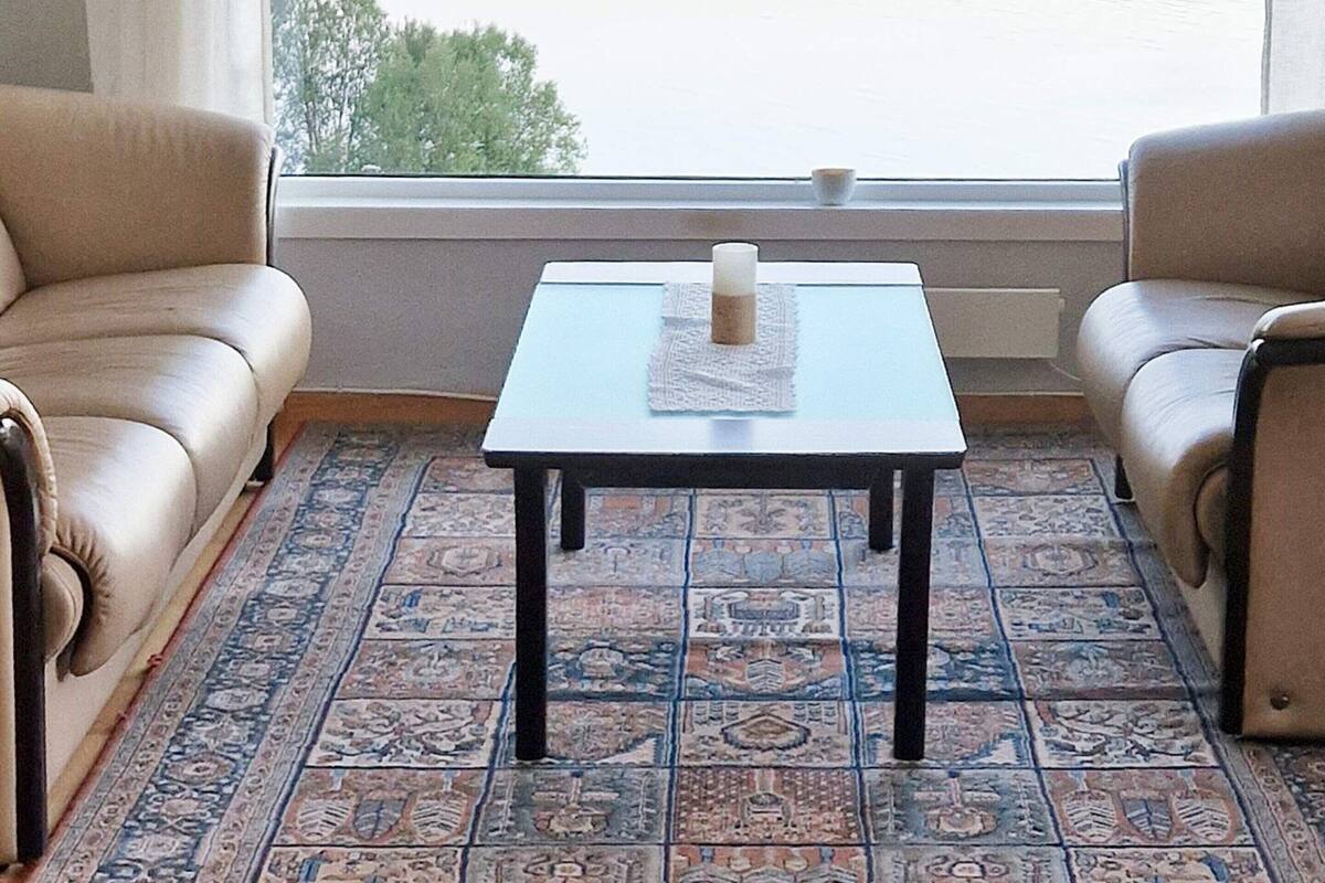 A room with a patterned floor, a small table with a candle, and two leather chairs.