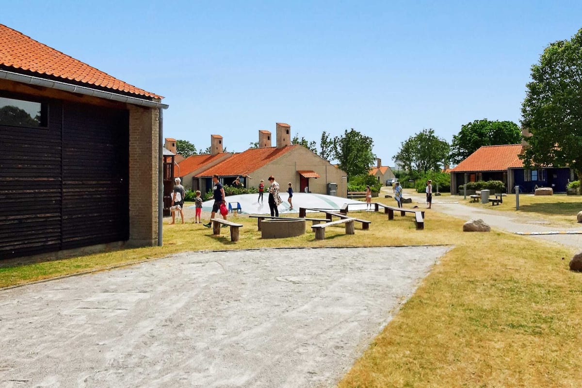 A courtyard with picnic tables, a playground, and a building with a red-tiled roof.