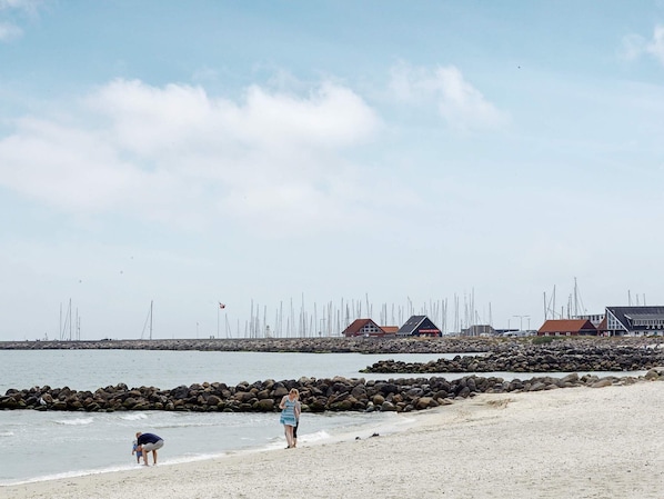A beach with a rocky shoreline, a few people, and buildings in the background.