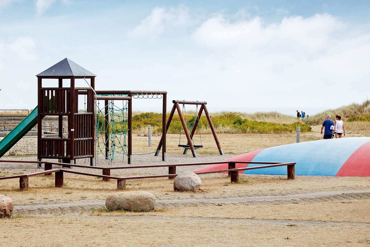 A playground with a climbing structure, swings, and a slide.